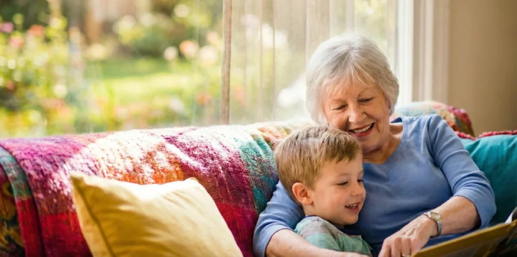 Großmutter und Enkel sitzen auf einer bunten Couch und blättern in einem Bilderbuch